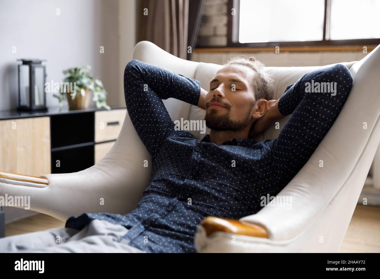Calm guy relaxing in pale comfortable armchair at home Stock Photo