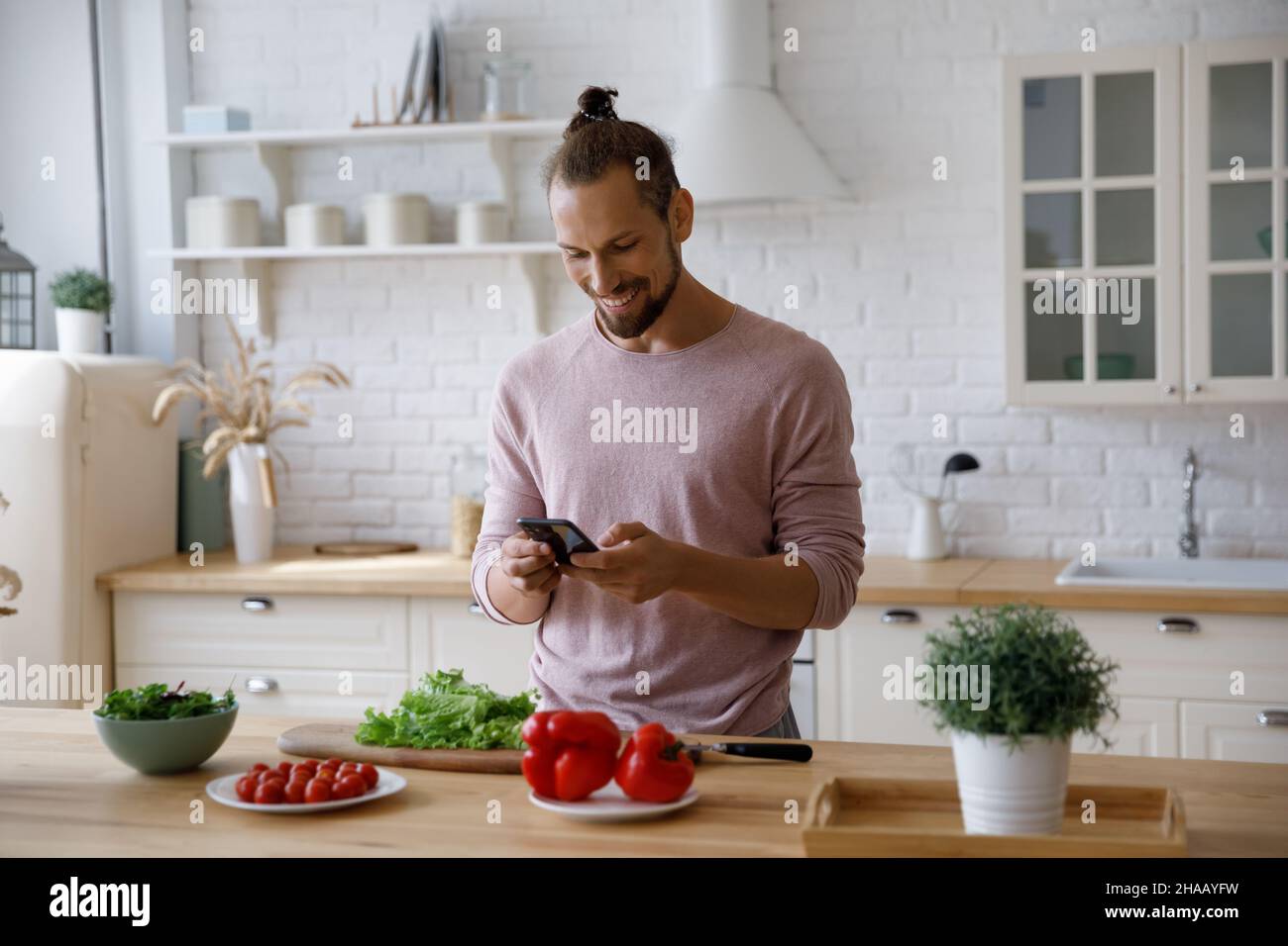 Happy cheerful millennial guy cooking salad in home kitchen Stock Photo