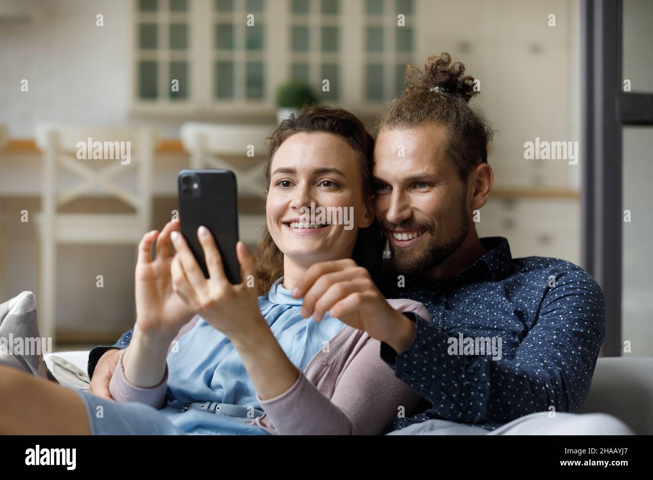 Happy cheerful millennial couple taking selfie on couch at home Stock Photo