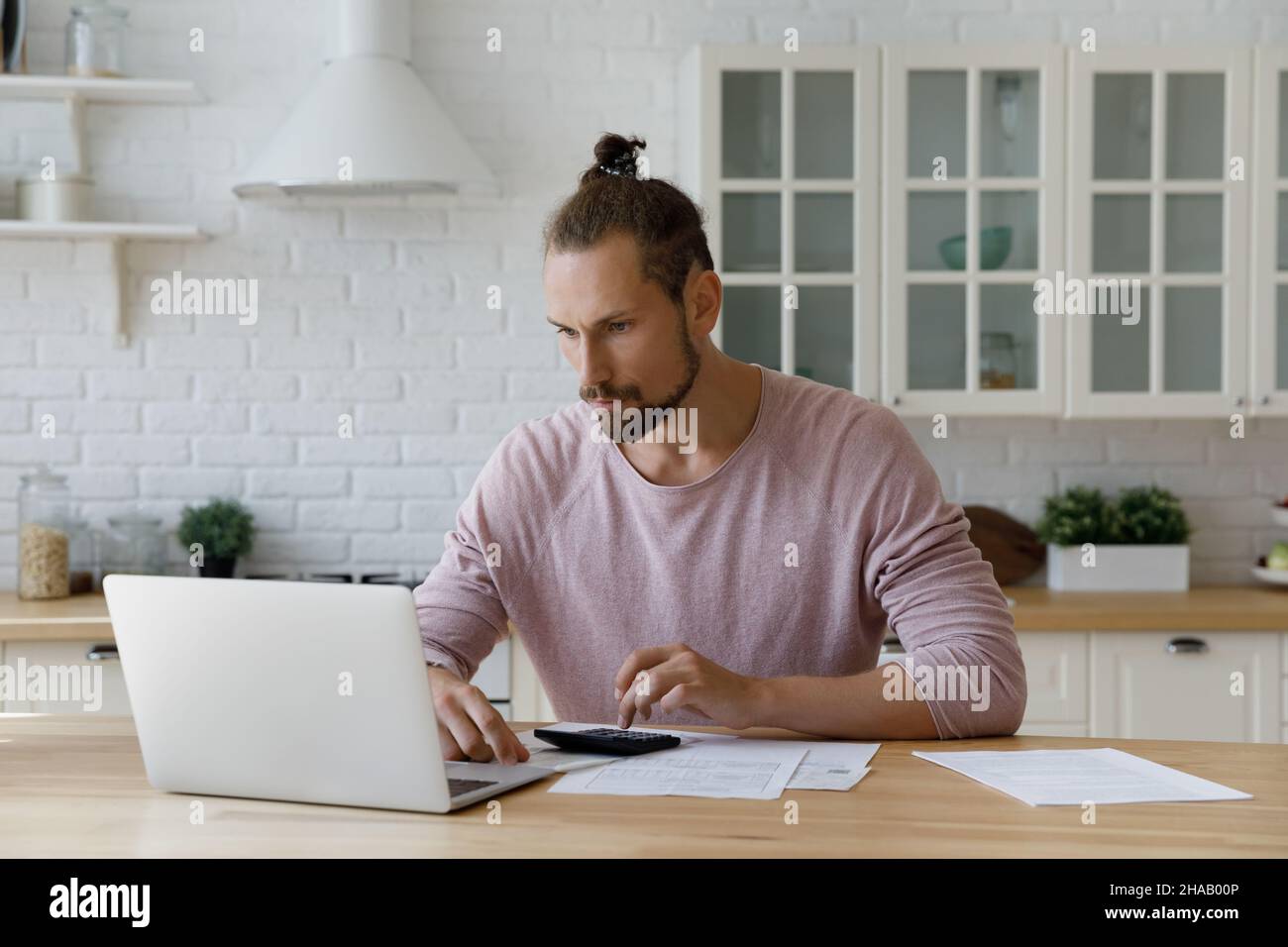 Focused bearded young hipster tenant man calculating mortgage fees Stock Photo