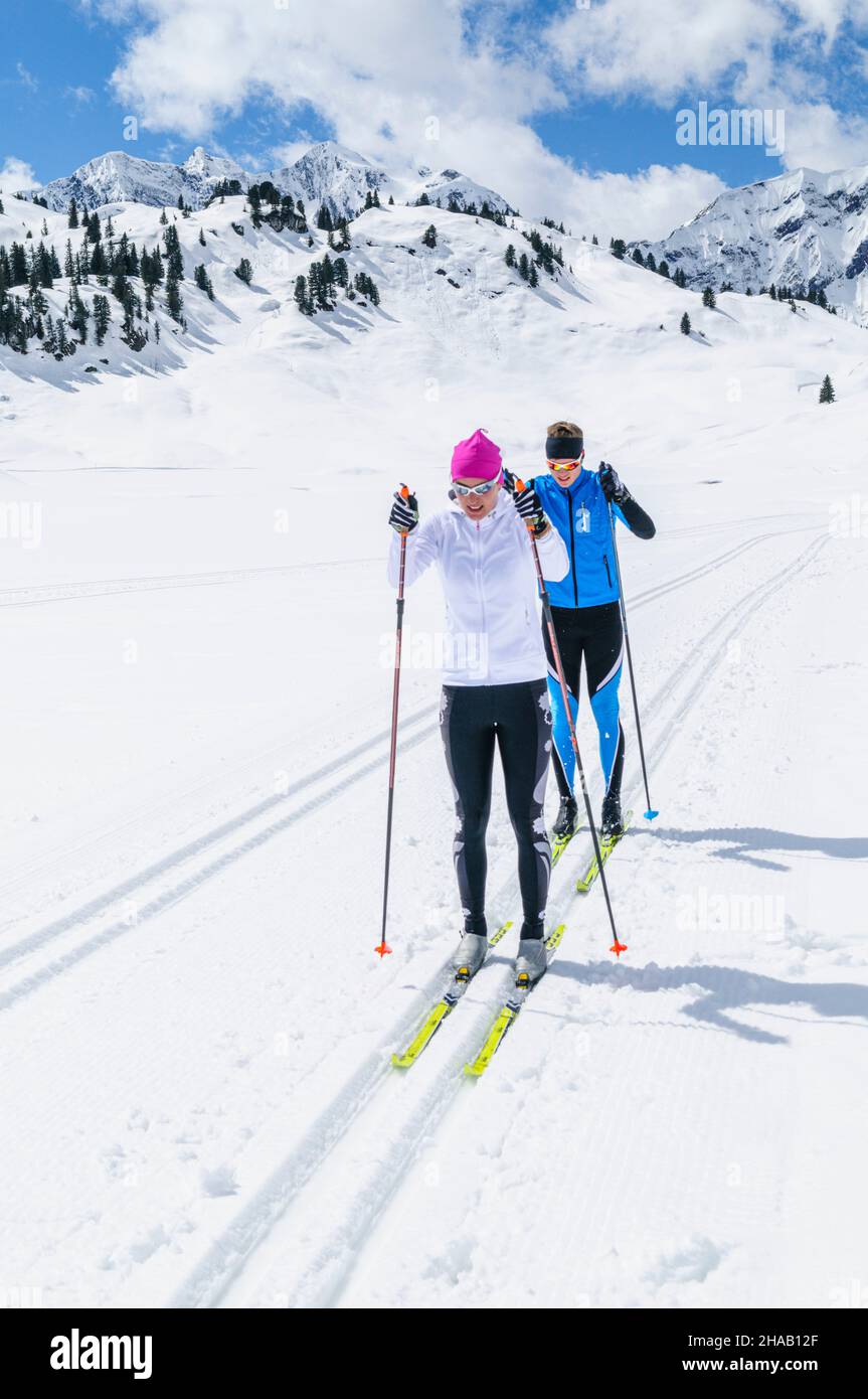 Two cross-country skiers are running in the classic style on a high mountain trail near the Hochtannberg Pass in Vorarlberg. Stock Photo