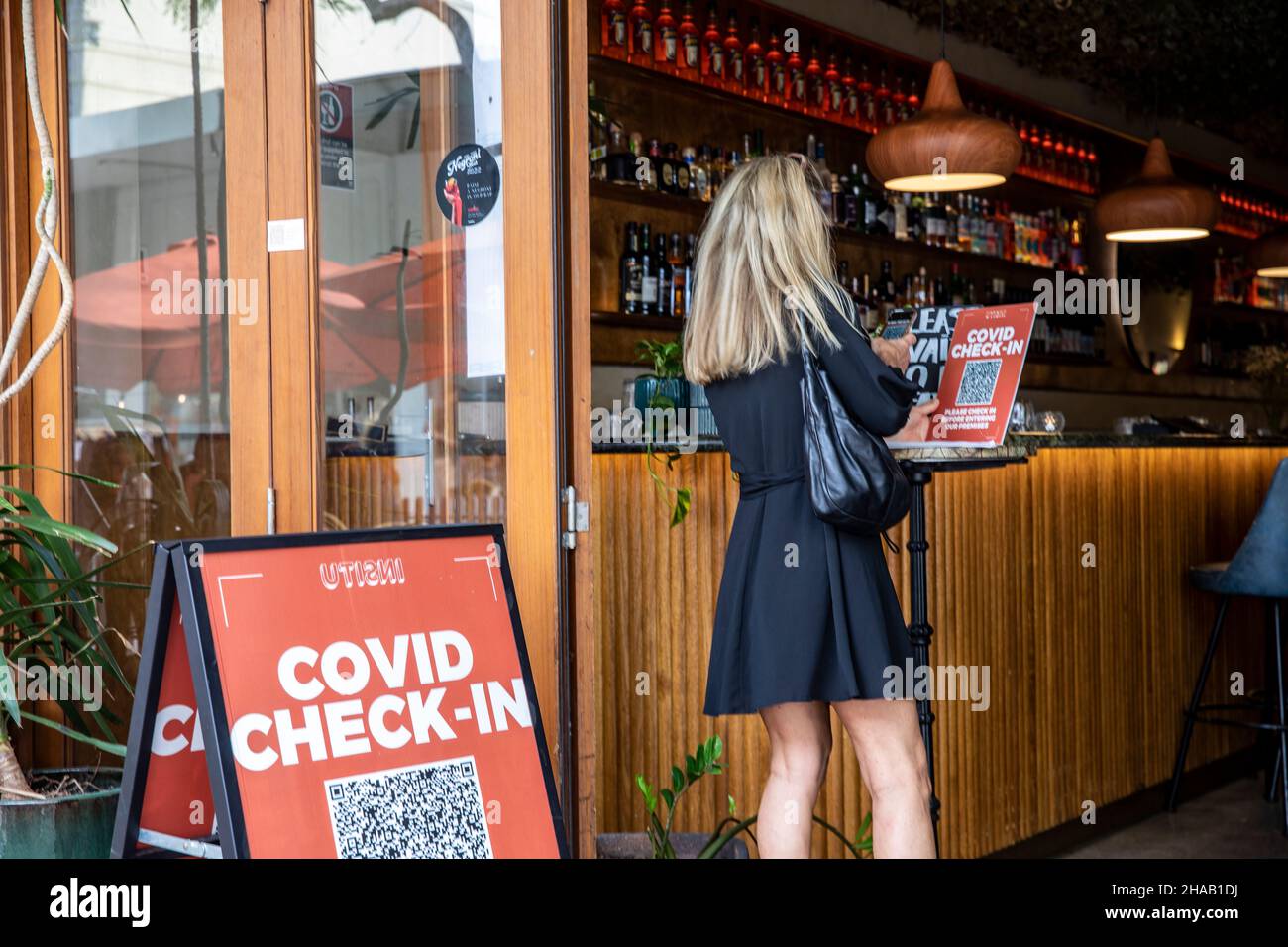 Covid 19 worldwide pandemic, in Sydney woman uses phone to scan app to check in at a restaurant bar, for contact tracing,Sydney,Australia Stock Photo