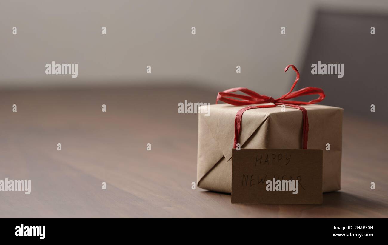 brown paper gift box with red bow on wood table with paper card, wide photo Stock Photo