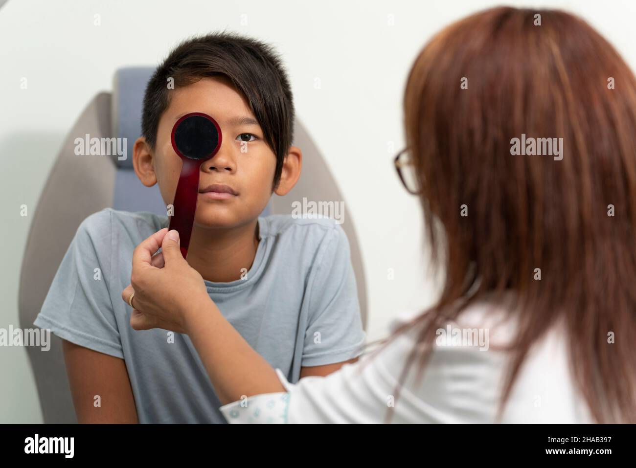 Asian boy in a consultation of an ophthalmologist woman Stock Photo