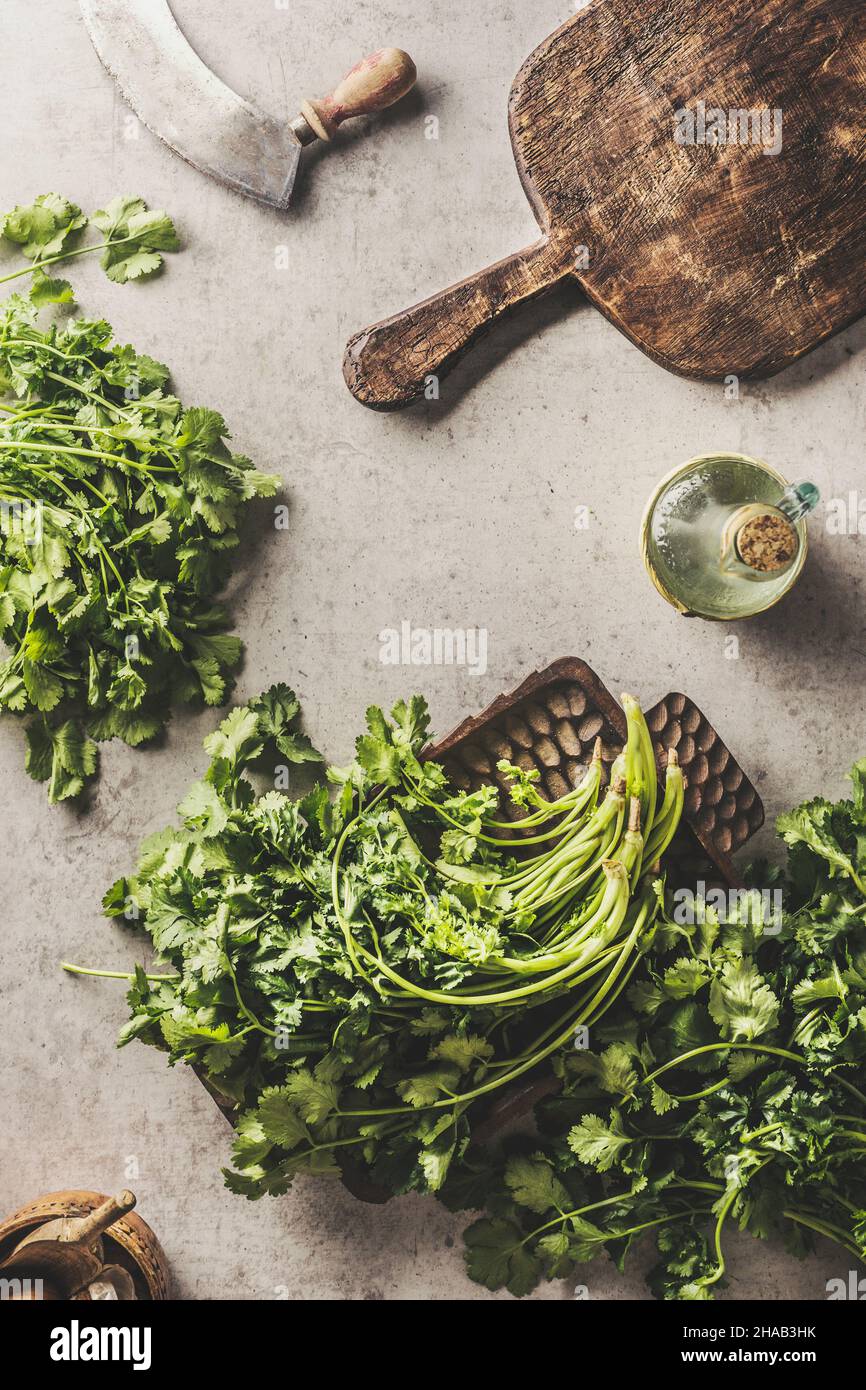 Fresh parsley on kitchen table with wooden cutting board and herbs knife. Cooking at home with healthy and flavorful ingredients. Top view. Stock Photo