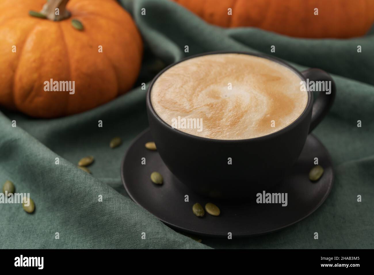 Pumpkin spicy latte in black cup on linne cloth, shallow focus Stock Photo