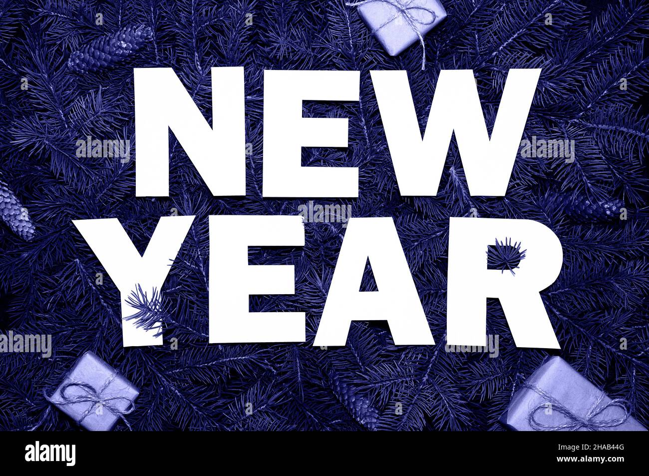 Words New Year on green fir branches with small gift boxs colored in