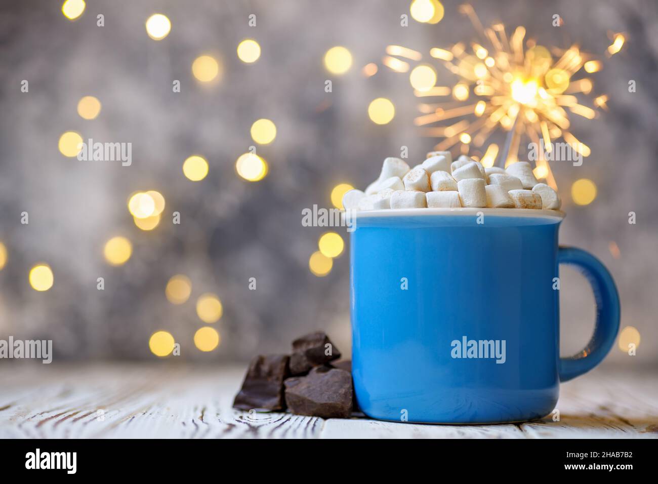 Hot chocolate with marshmallow and burning sparkler on wooden table Stock Photo