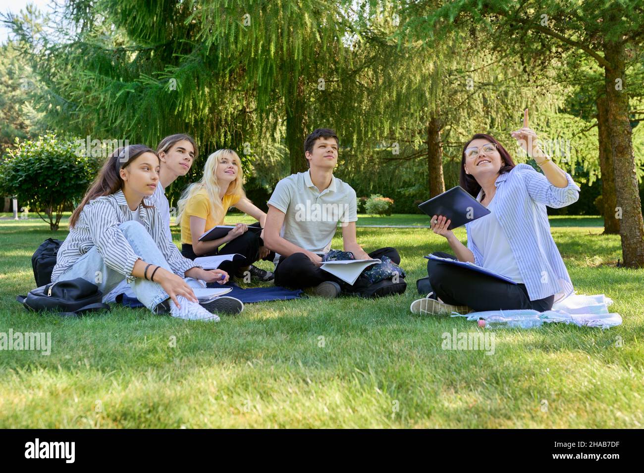 Outdoor, group of students with female teacher sitting on grass Stock ...