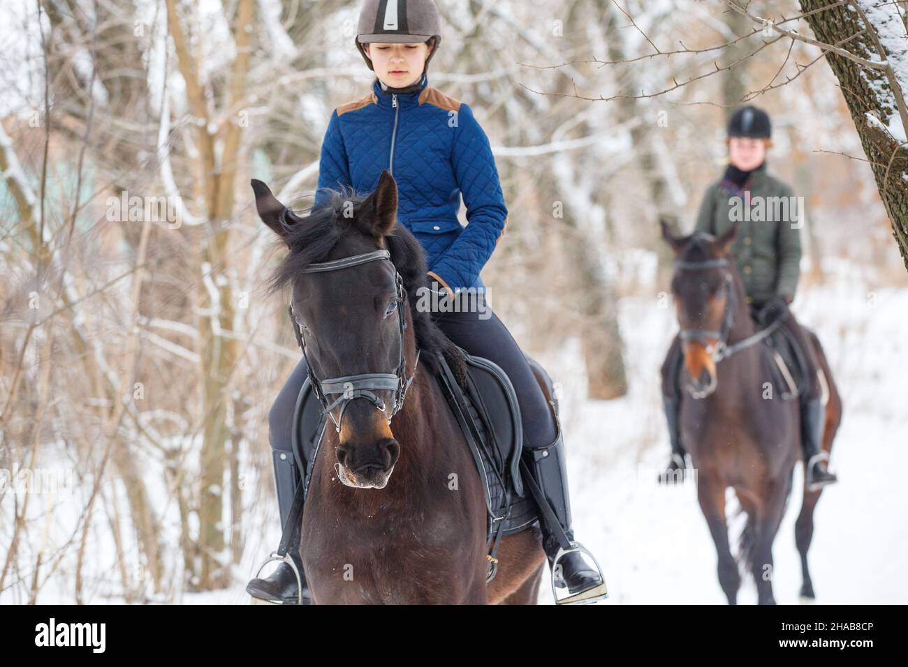 Two young girls riding horse in snowy park in winter Stock Photo
