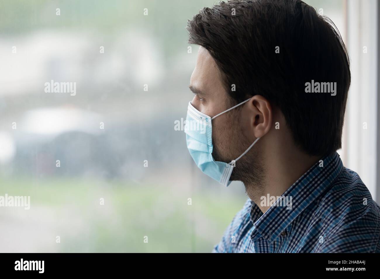 Man wear blue protective face mask looks out window Stock Photo - Alamy