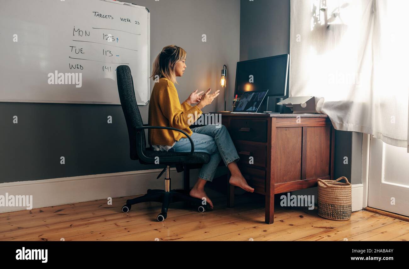 Young businesswoman attending a virtual meeting while working in her home office. Focused female entrepreneur explaining her strategy to her business Stock Photo