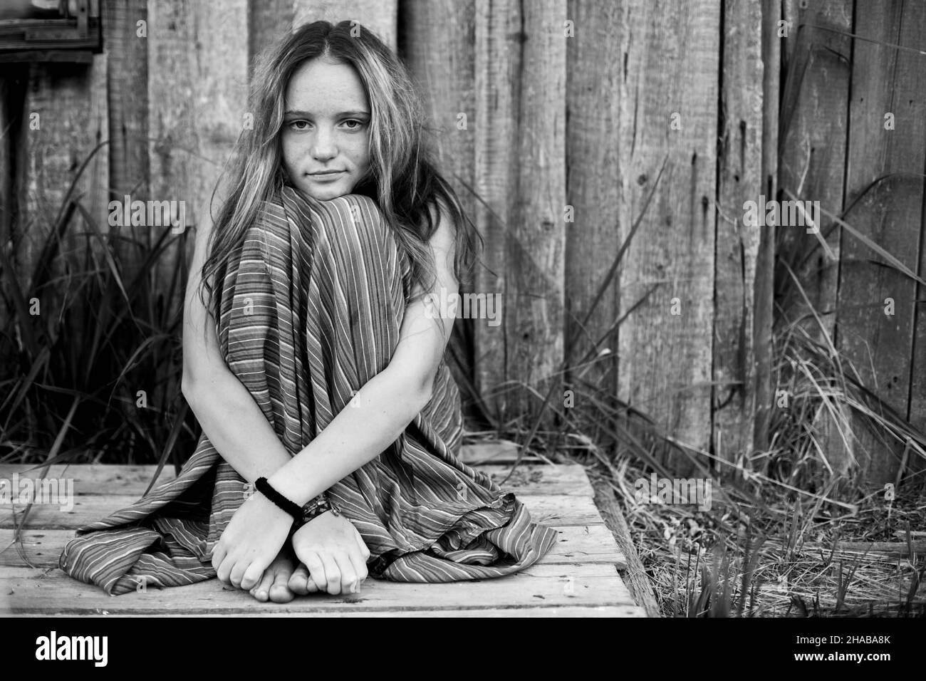 Country girl sits in the yard of her house. Black and white photo. Stock Photo