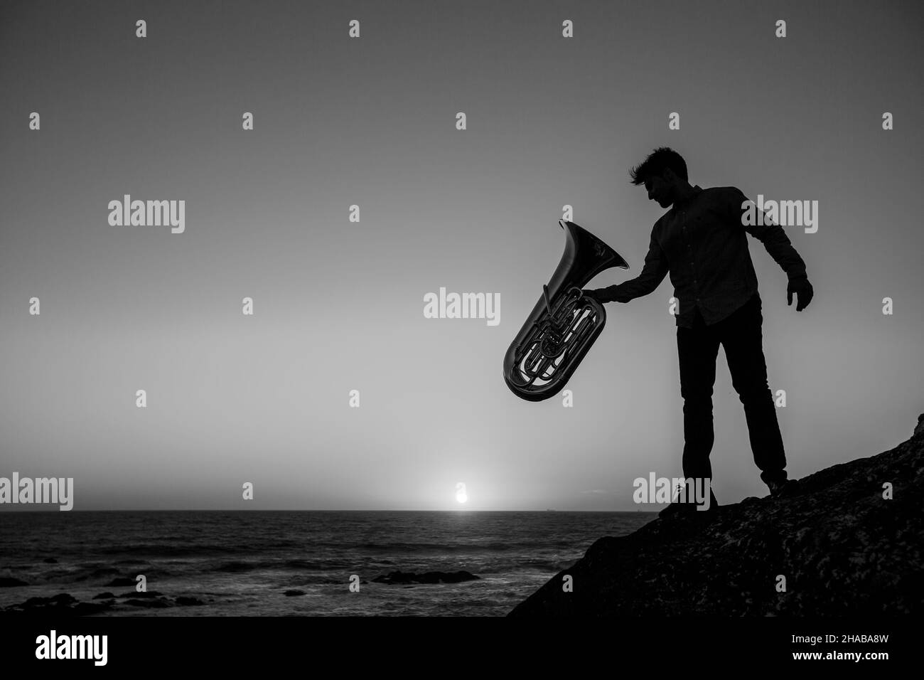 Silhouette of a man with a trumpet by the ocean. Black and white photo. Stock Photo