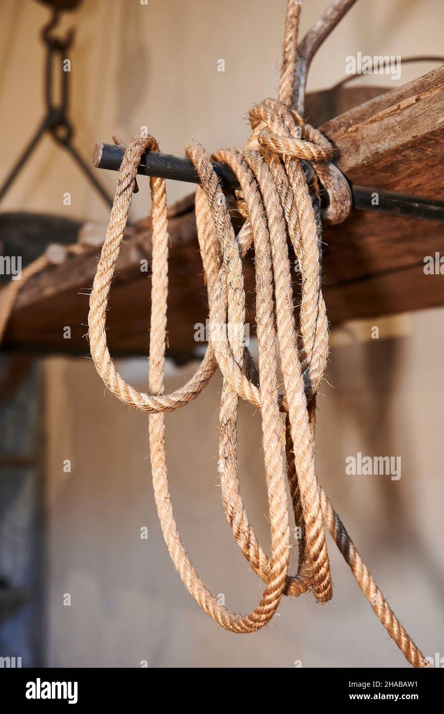 Detail of an old hemp rope hanging from an iron bar and a wooden
