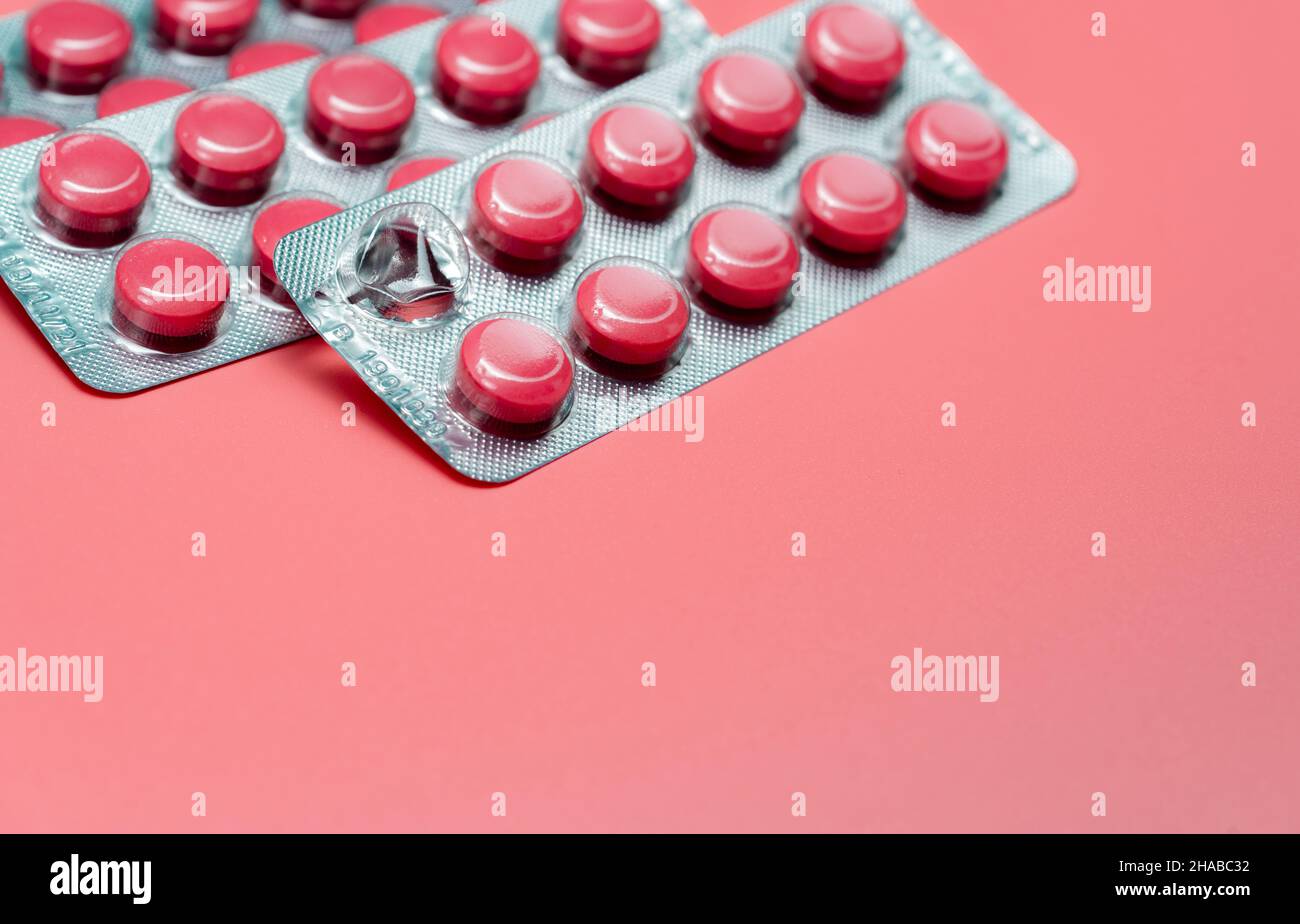 Pink round tablets pills in blister pack on pink background. Painkiller medicine. Take pill. Pharmacy product package. Pharmaceutical industry. Stock Photo