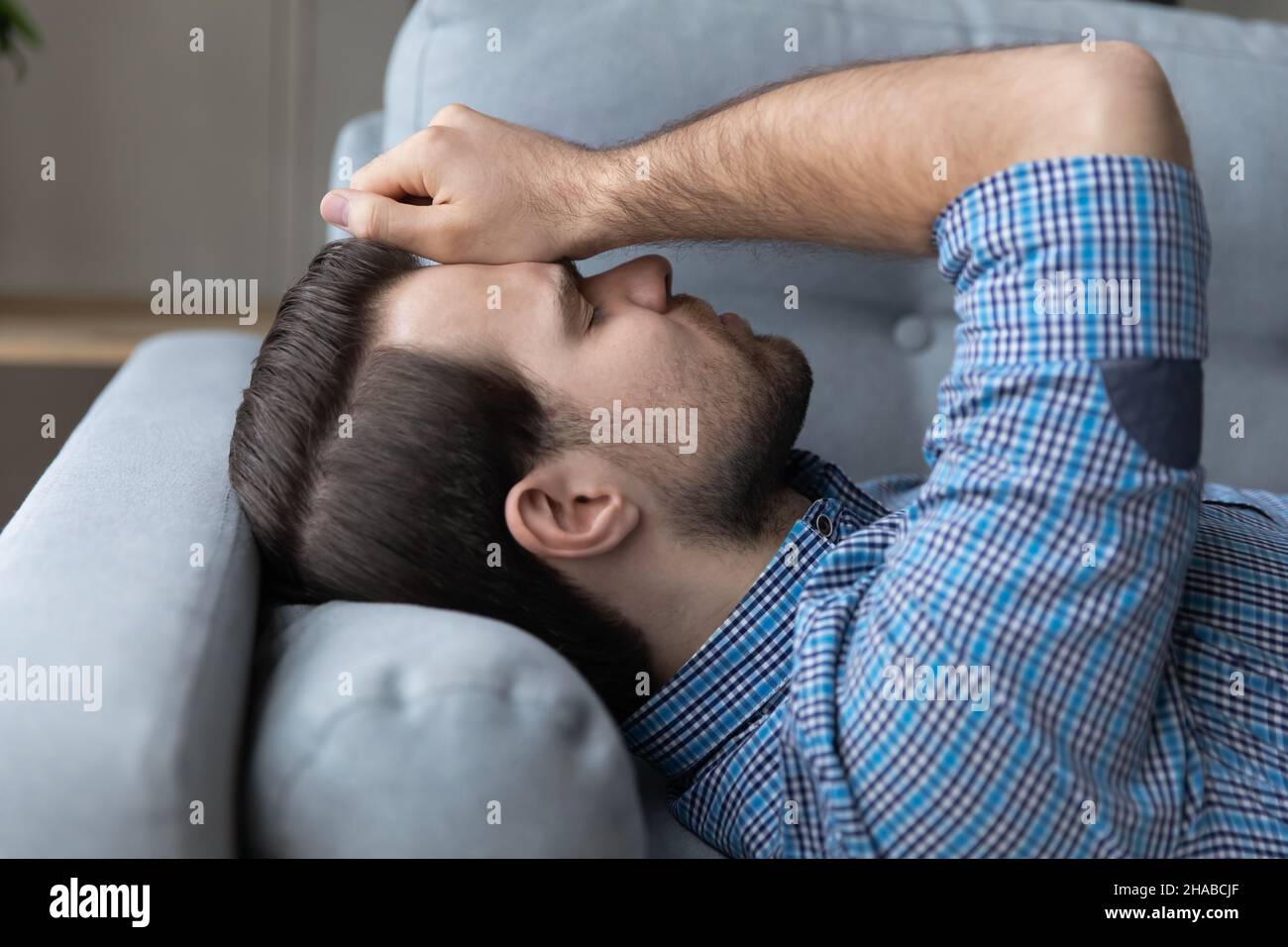 Closeup young man lying on couch suffers from headache Stock Photo Alamy