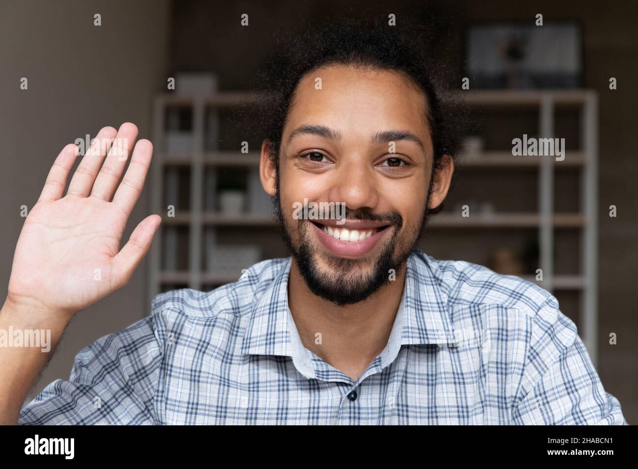 Closeup smiling African guy wave hand start videocall webcam view Stock Photo