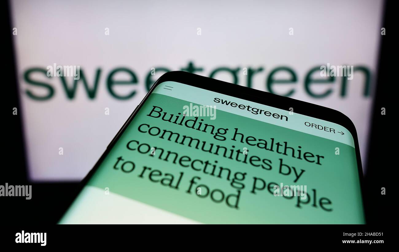 Mobile phone with website of fast casual restaurant chain Sweetgreen Inc. on screen in front of business logo. Focus on top-left of phone display. Stock Photo