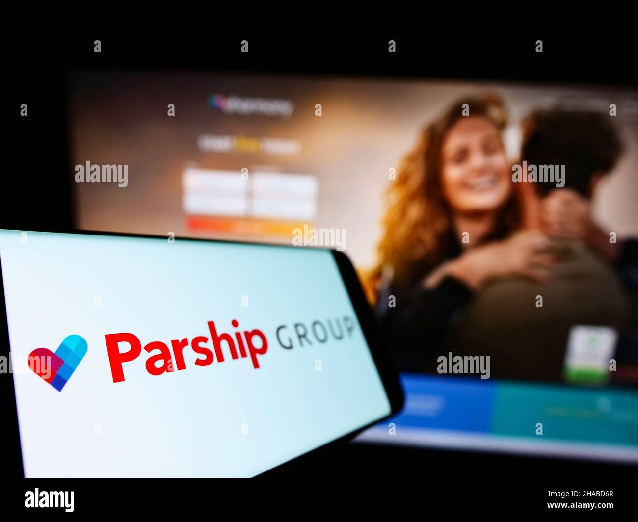 Mobile phone with logo of German online dating company ParshipMeet Holding GmbH on screen in front of website. Focus on left of phone display. Stock Photo