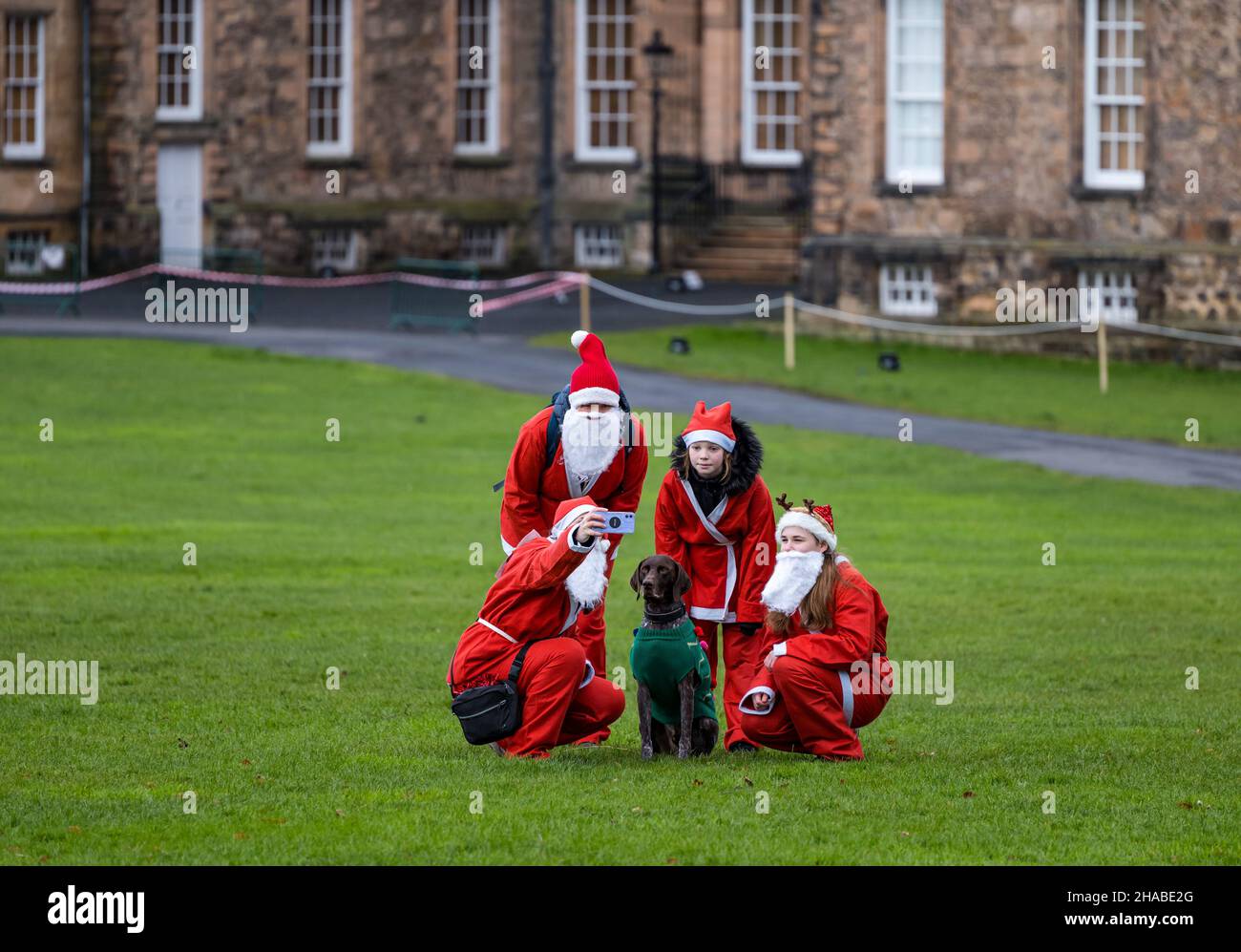 Dalkeith, Midlothian, Scotland, United Kingdom, 12th December 2021. Santa Run and Elf Dash: the charity fund-raising event takes place in Dalkeith Country Park to raise money for CHAS (Children’s Hospices Across Scotland) Pictured: a family taking part in the Santa Run take a selfie photo before the event. Stock Photo