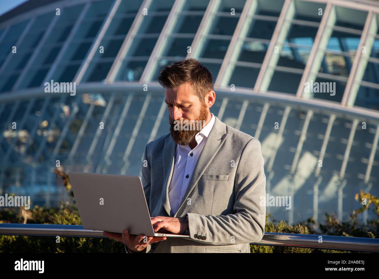 businessman with laptop in an urban setting modern buildings in background Stock Photo