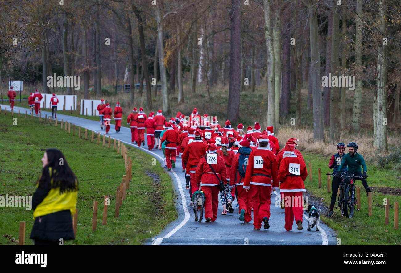 Dalkeith, Midlothian, Scotland, United Kingdom, 12th December 2021. Santa Run and Elf Dash: the charity fund-raising event takes place in Dalkeith Country Park to raise money for CHAS (Children’s Hospices Across Scotland) Pictured: participants in the Santa Run dash off into the woodland estate Stock Photo