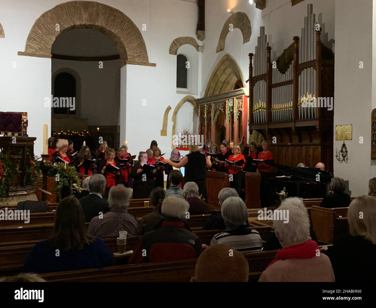 All Saints Brixworth Church Northamptonshire UK singing Queen Eleanor Choir singing sing songs Northampton pews pew Congregation  arch arches Stock Photo