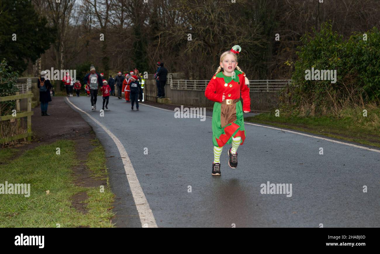 Dalkeith, Midlothian, Scotland, United Kingdom, 12th December 2021. Santa Run and Elf Dash: the charity fund-raising event takes place in Dalkeith Country Park to raise money for CHAS (Children’s Hospices Across Scotland) Pictured: participants in the Elf Dash for the younger children with a grill running dressed in an elf costume Stock Photo