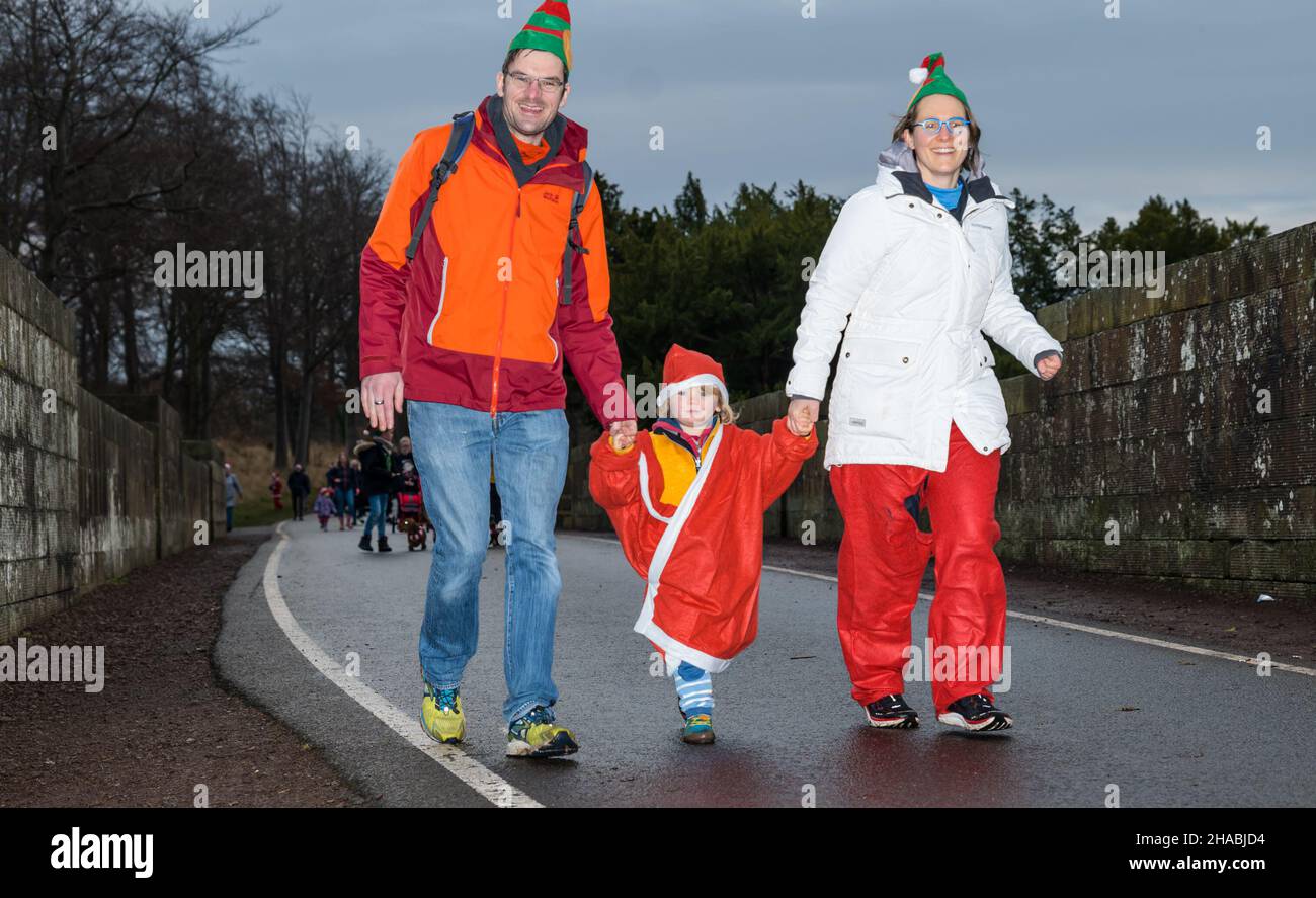 Dalkeith, Midlothian, Scotland, United Kingdom, 12th December 2021. Santa Run and Elf Dash: the charity fund-raising event takes place in Dalkeith Country Park to raise money for CHAS (Children’s Hospices Across Scotland) Pictured: participants in the Elf Dash for the younger children with two parents running with a small child Stock Photo