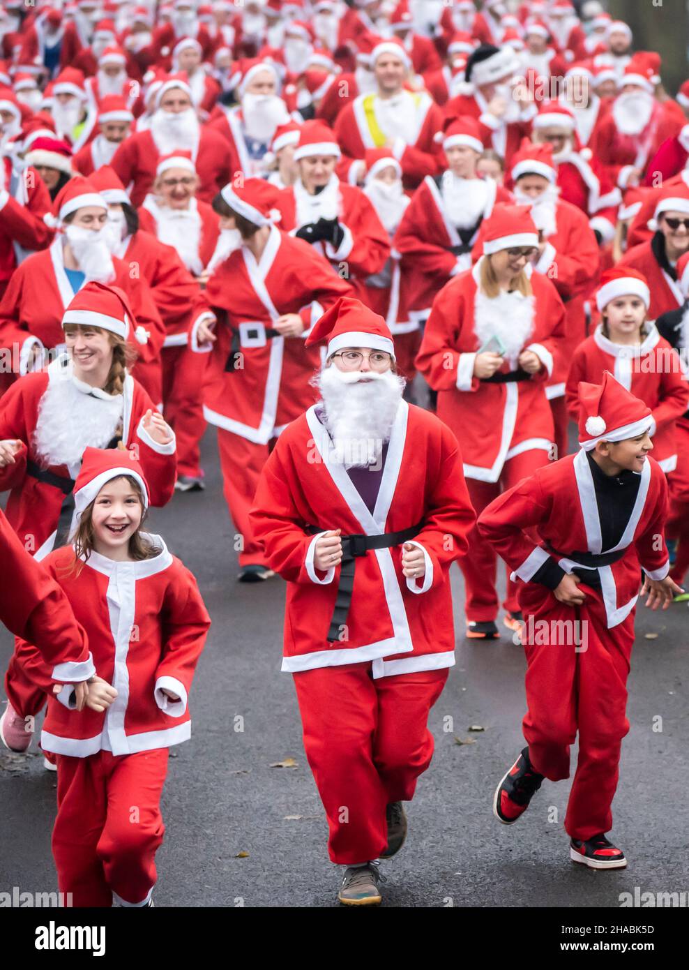 People take part in the Big Leeds Santa Dash in Roundhay Park, Leeds, Yorkshire. Hundreds of people donned Santa suits and joined the 5k fun run organised by St Gemma's Hospice, a charity providing expert care and support people with cancer and other life-threatening illnesses. Picture date: Sunday December 12, 2021. Stock Photo