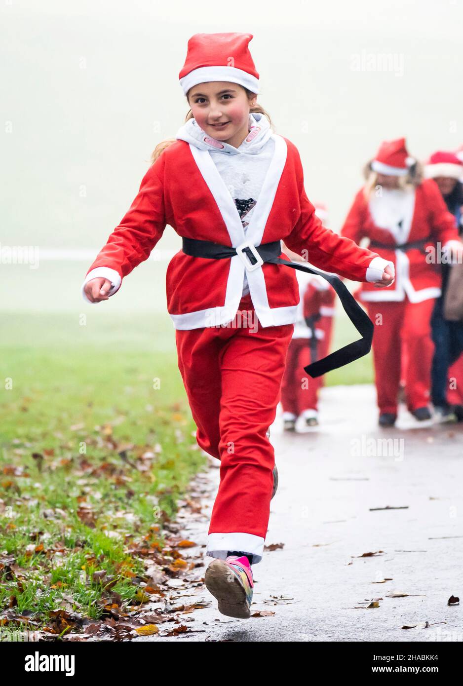 People take part in the Big Leeds Santa Dash in Roundhay Park, Leeds, Yorkshire. Hundreds of people donned Santa suits and joined the 5k fun run organised by St Gemma's Hospice, a charity providing expert care and support people with cancer and other life-threatening illnesses. Picture date: Sunday December 12, 2021. Stock Photo