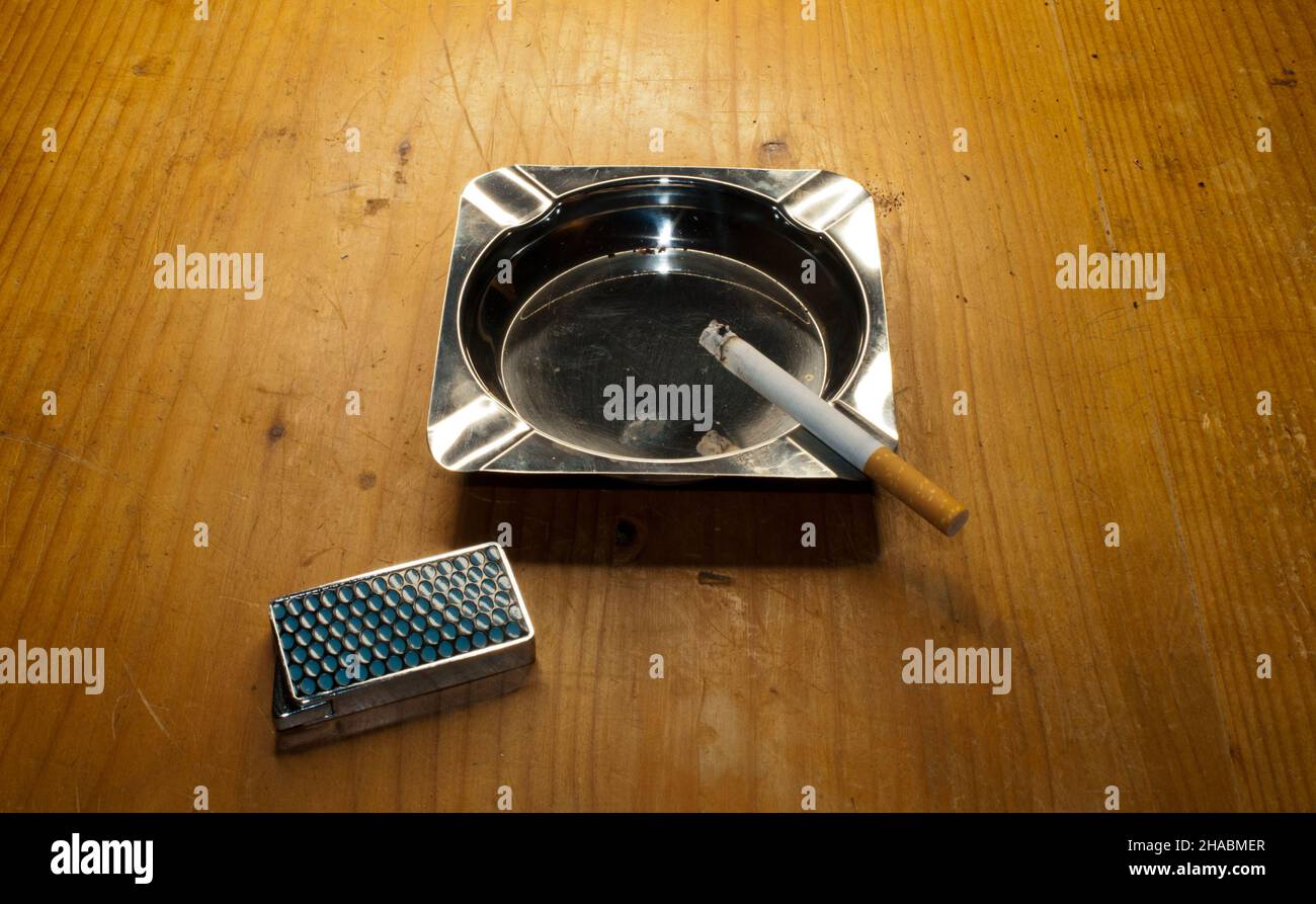 Ashtray with burning cigarette and lighter Stock Photo Alamy