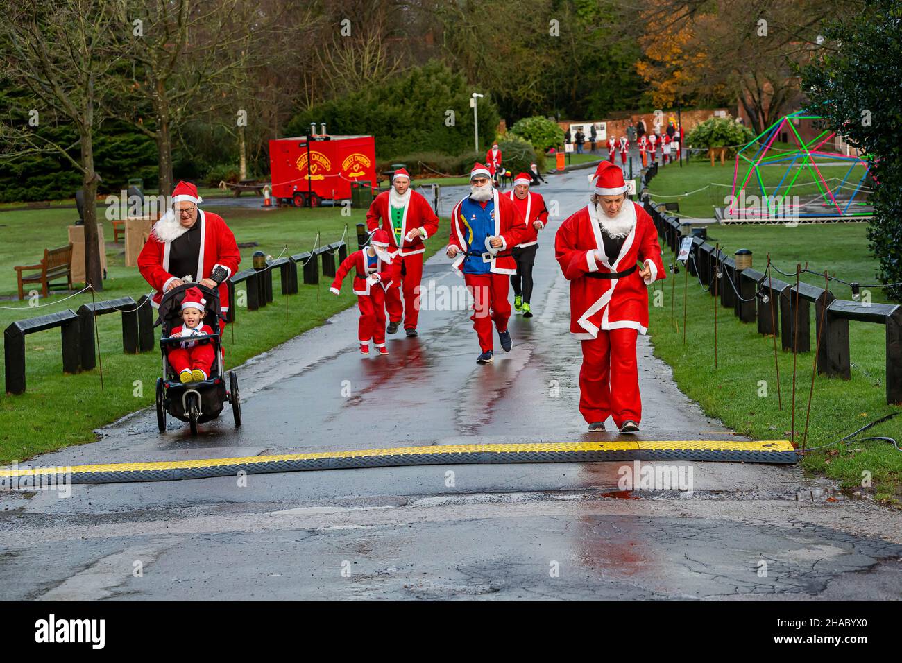 Warrington, UK. Sunday 12 December 2021 - Walton Hall and Gardens. After a year's break the annual 3K Santa Dash/Santa Walk organised by Warrington Disability Partnership even though the weather was raining at the start. There was a hill where people struggled. Families also took part Credit: John Hopkins/Alamy Live News Stock Photo