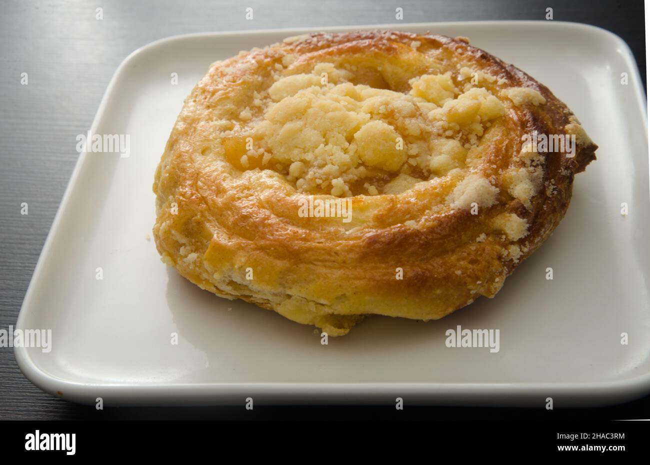Apple crumb danish on white plate, simplistic concept  one of the necessities of life & enjoyment. Stock Photo