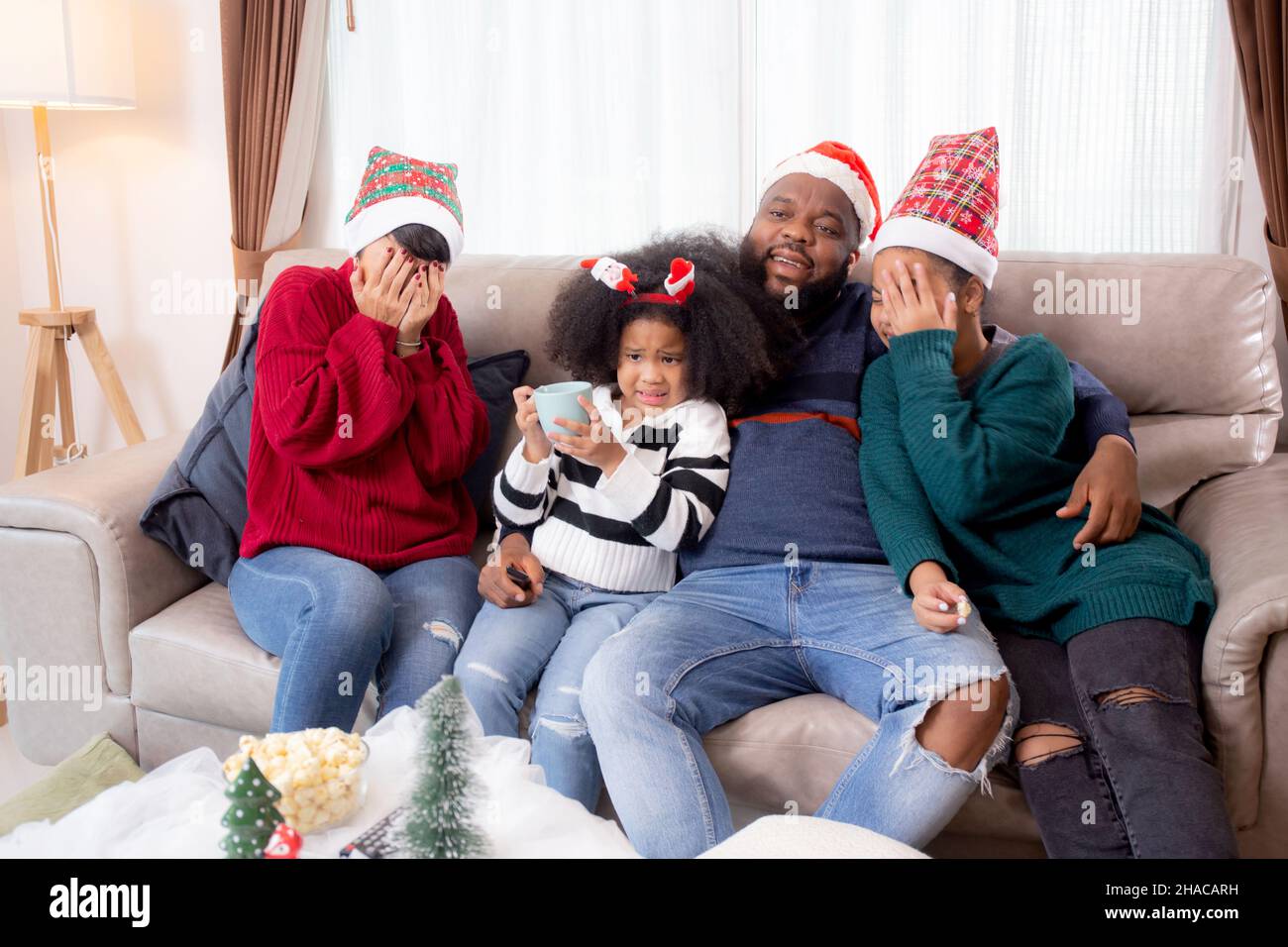 Happy African family sitting on couch watching TV with horror movie in ...