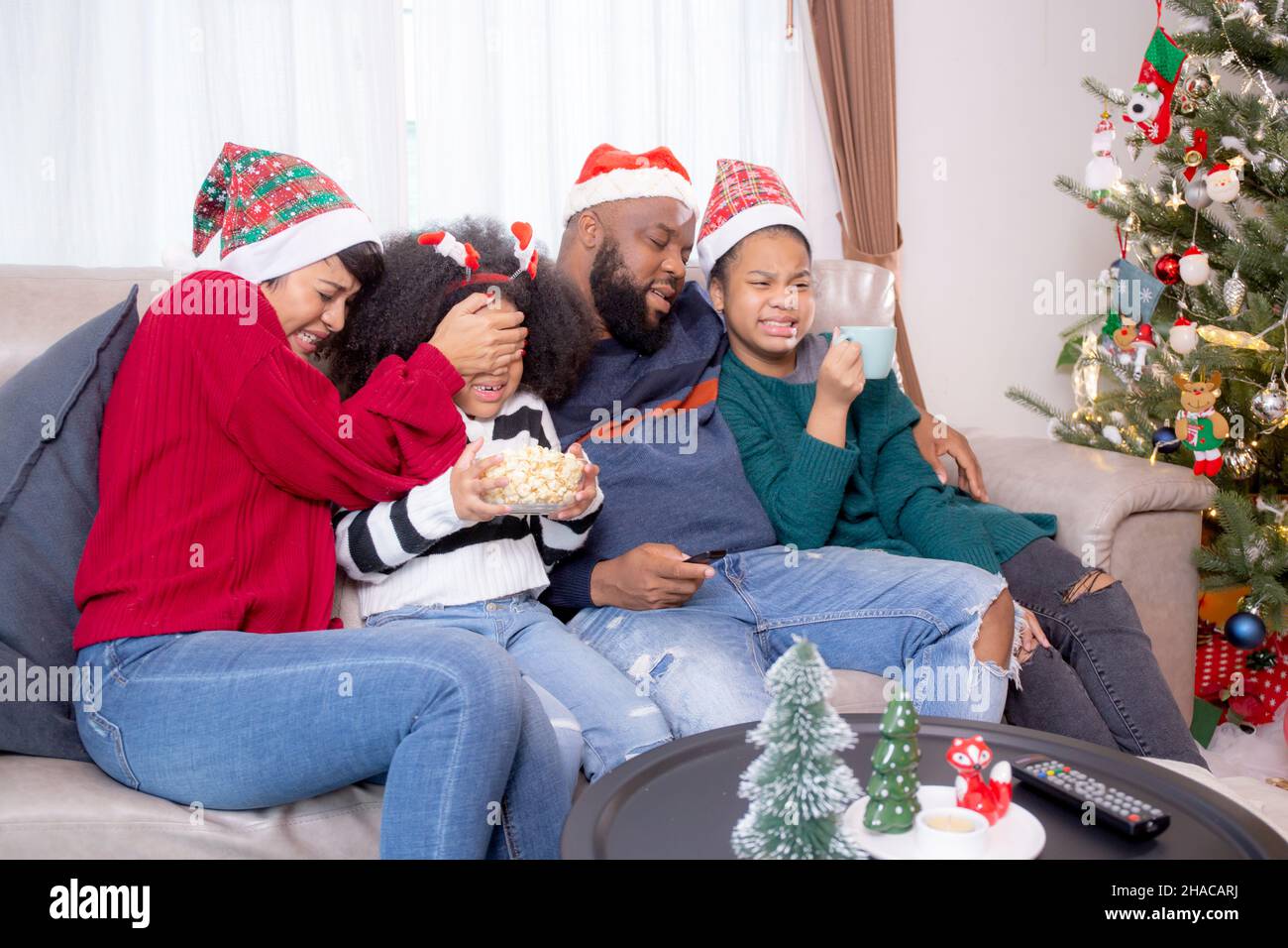 Happy African family sitting on couch watching TV with horror movie in ...