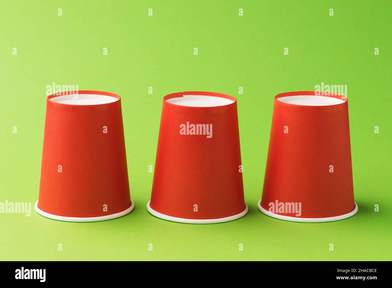 Inverted red paper cups on a green background Stock Photo