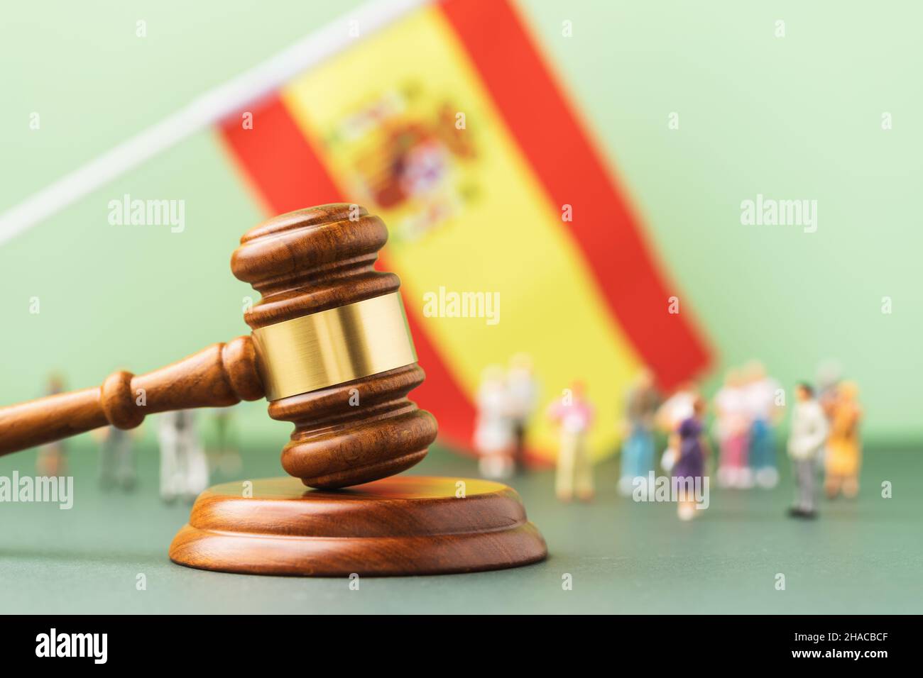 Judge gavel, flag of Spain and plastic toy men on a colored background