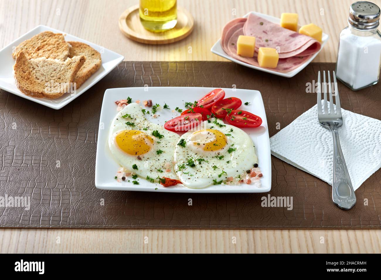 Fried eggs with cherry tomatoes, cheese and salami Stock Photo