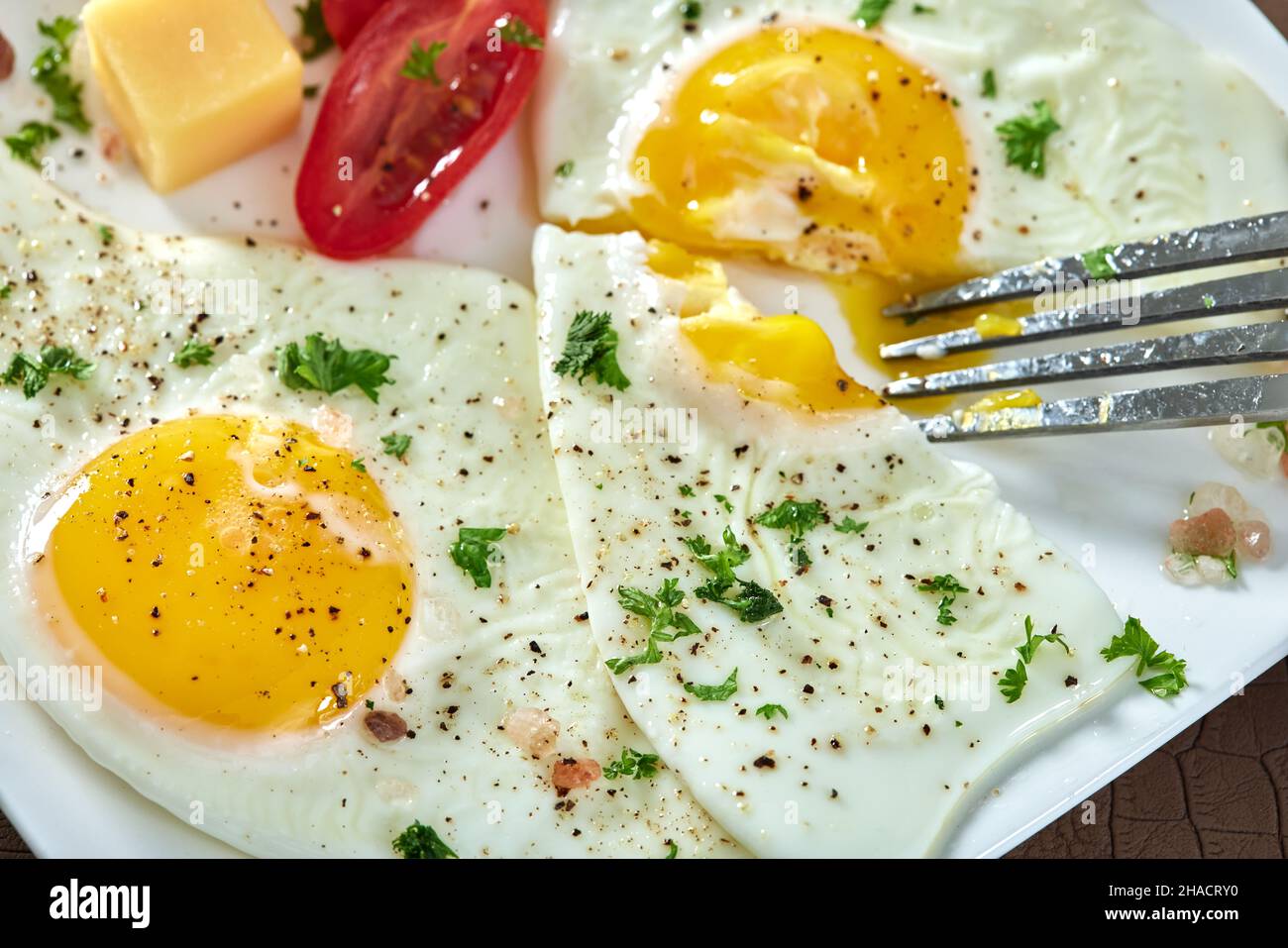 Eating Fried eggs with cherry tomatoes and cheese Stock Photo