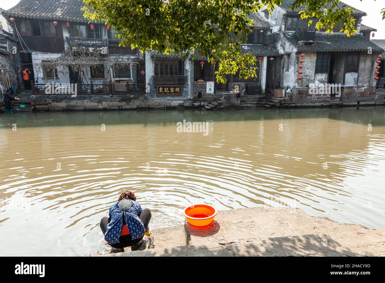Woman washing her clothes in a canal in the water village of Xitang, China Stock Photo