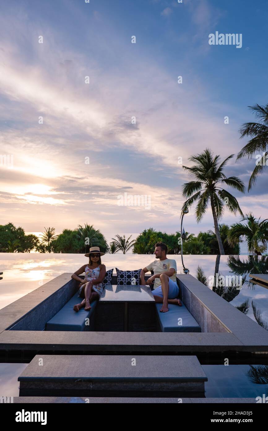 couple man and woman watching sunset from a rooftop infinity pool on a ...