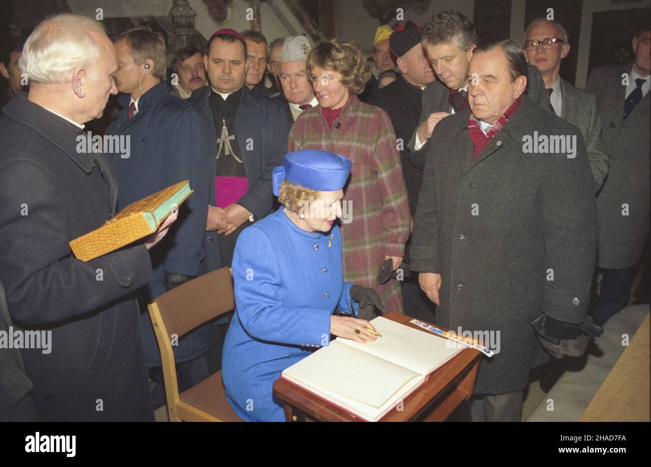 Warszawa 02.11.1988. Oficjalna wizyta premier Wielkiej Brytanii Margaret Thatcher w Polsce. Nz. angielska premier wpisuje siê do ksiêgi pamiêci grobu ksiêdza Jerzego Popie³uszki na terenie koœcio³a pw. œw. Stanis³awa Kostki na ¯oliborzu. W g³êbi biskup pomocniczy archidiecezji warszawskiej Marian Duœ. js  PAP/Jan Morek         Warsaw 02 November 1988. The official visit of British Prime Minister Margaret Thatcher to Poland. Pictured: the British PM making an entry in the Remembrance Book of father Jerzy Popieluszko's grave at the premises of the Stanislaw Kostka Catholic church in Zoliborz. In Stock Photo