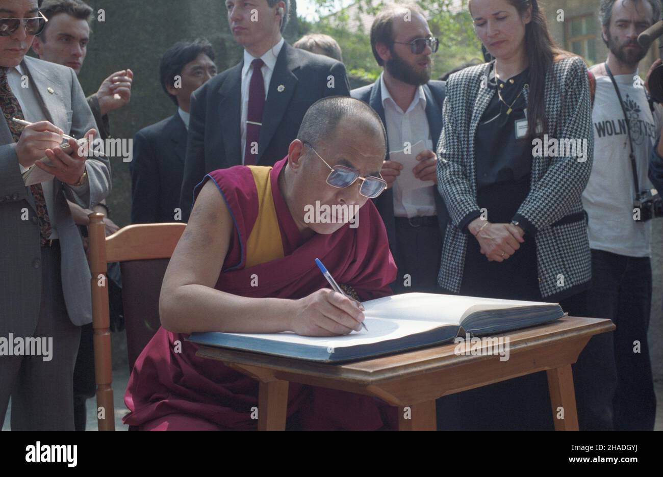 Oœwiêcim 18.05.1993. Na zaproszenie Helsiñskiej Fundacji Praw Cz³owieka przylecia³ do Polski Dalajlama XIV, duchowy i polityczny przywódca narodu tybetañskiego, laureat pokojowej nagrody Nobla. Nz. Dalajlama wpisuje siê w ksiêgê pami¹tkow¹ na terenie by³ego niemieckiego obozu zag³ady KL Auschwitz-Birkenau. W g³êbi reporter PAP Zbigniew Krzysztyniak (C). ka  PAP/Jacek Bednarczyk         Oswiecim 18 May 1993. Tibetan spiritual leader, Nobel Prize winner the Dalai Lama visits Poland on an invitation from the Helsinki Foundation for Human Rights. Pictured: the Dalai Lama signs a visitors' book at Stock Photo