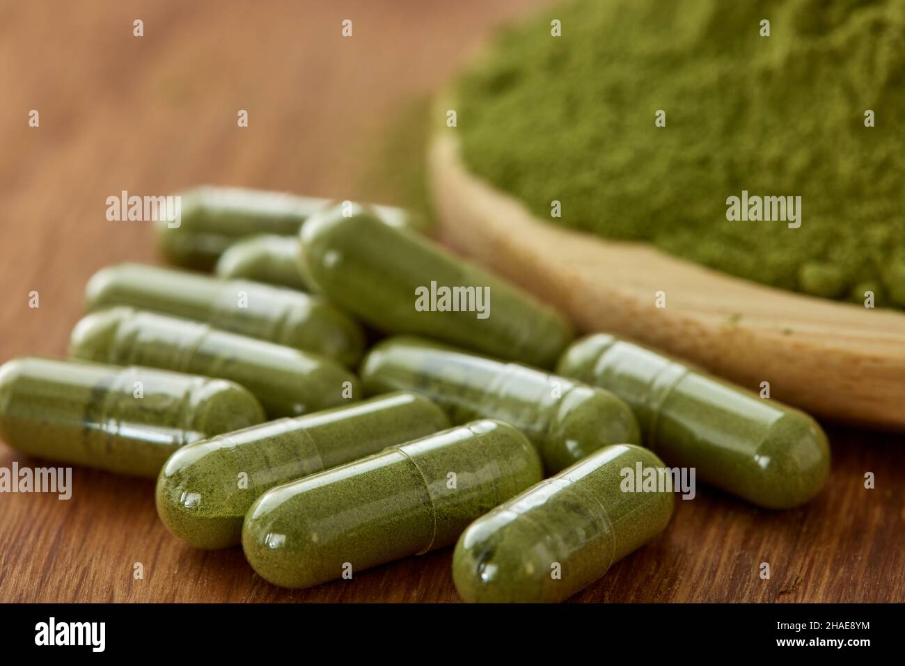Capsules filled with Moringa powder on wooden background - close up view Stock Photo