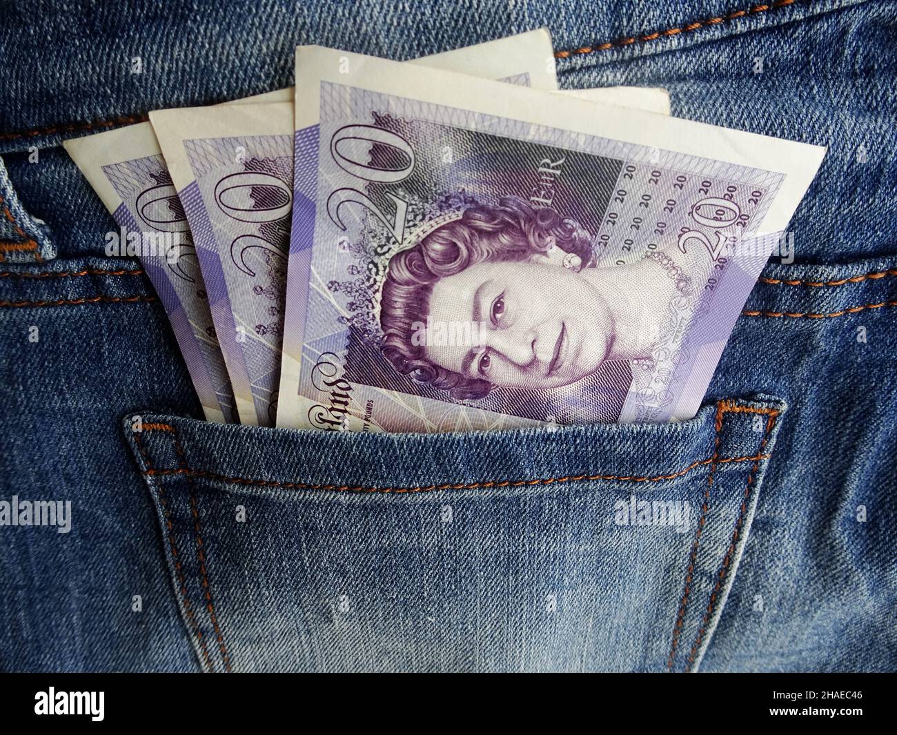 Twenty pounds notes stick out from jeans pocket Stock Photo