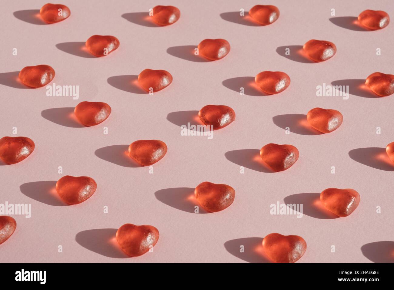 Pattern made of soft candy hearts arranged on light pink background. Love, affection minimal concept. Stock Photo