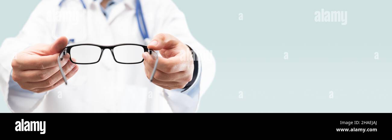Eye doctor, oculist in clinic. Optometrist holds glasses to try on. Web banner copy space image Stock Photo