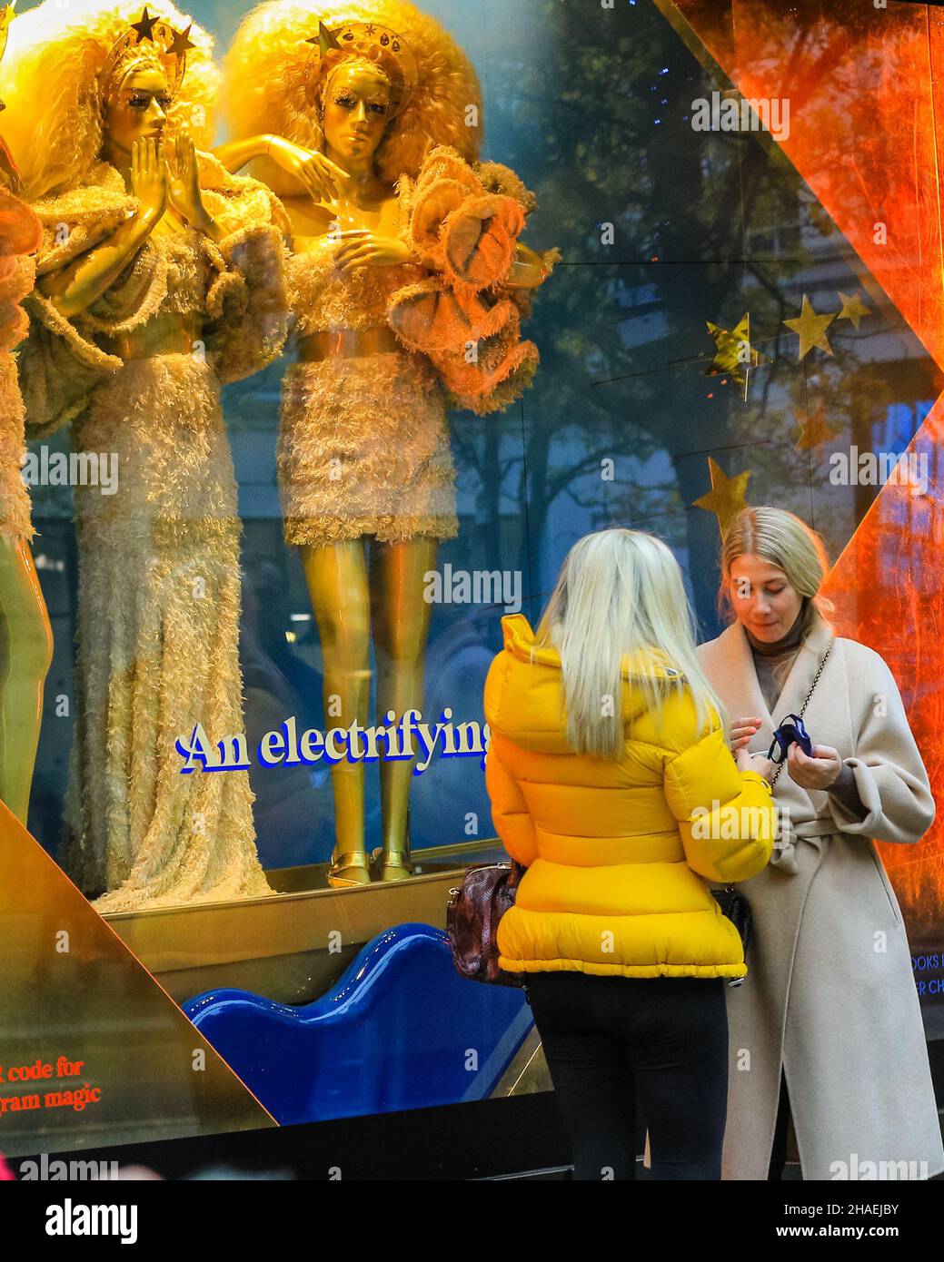 Oxford Street London, UK, 12th Dec 2021. People walk past and look at the flamboyant, colourful window decorations at Selfridges. Shoppers and visitors to London crowd into busy Oxford Street today despite infection rates with the new omnicron covid variant in London, and the wider country, rising fast, and government considering the introduction of further measures to curb the trend. Stock Photo